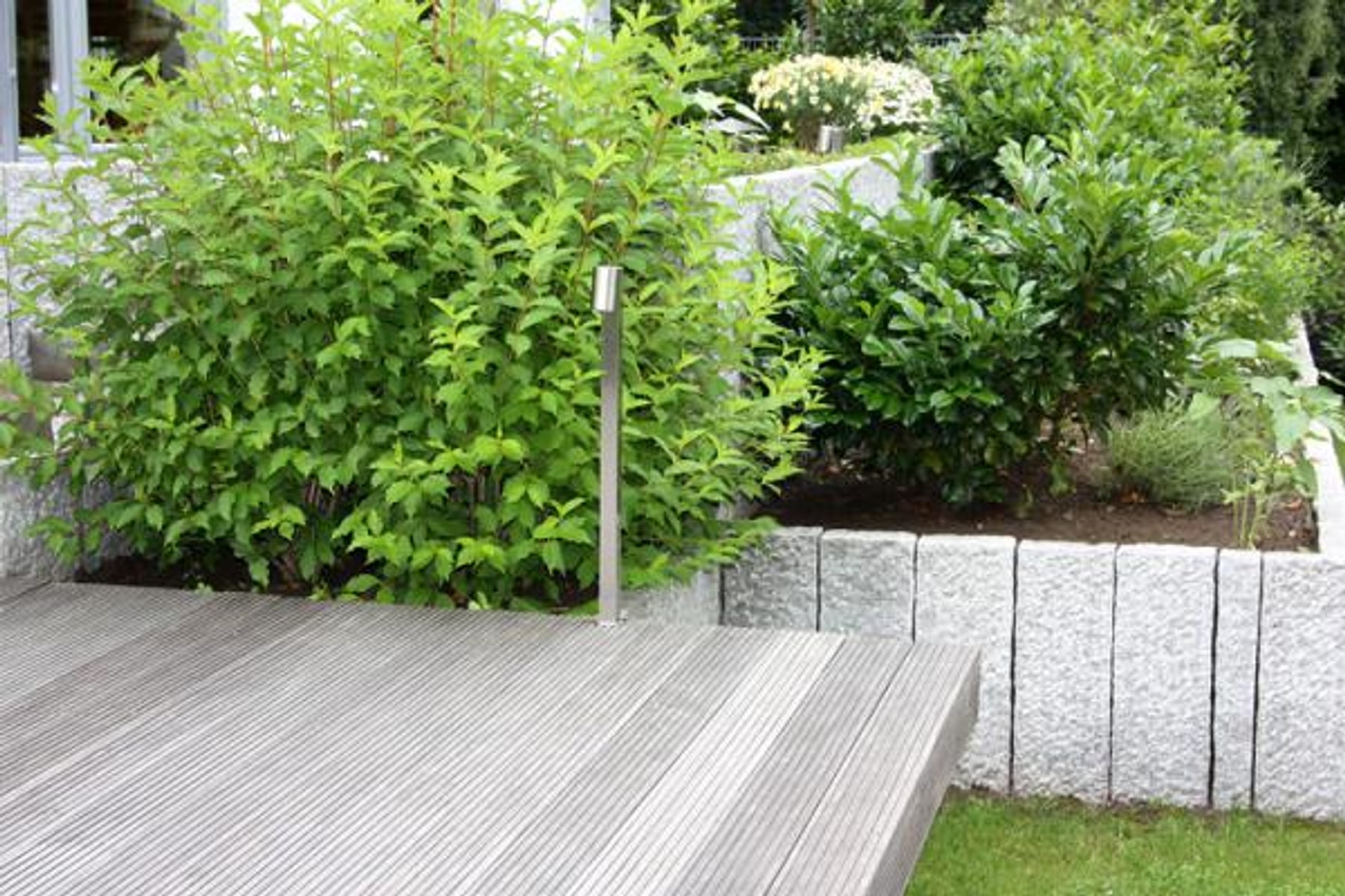 Terrassenanlage mit Holz, Granitmauer und Bepflanzung