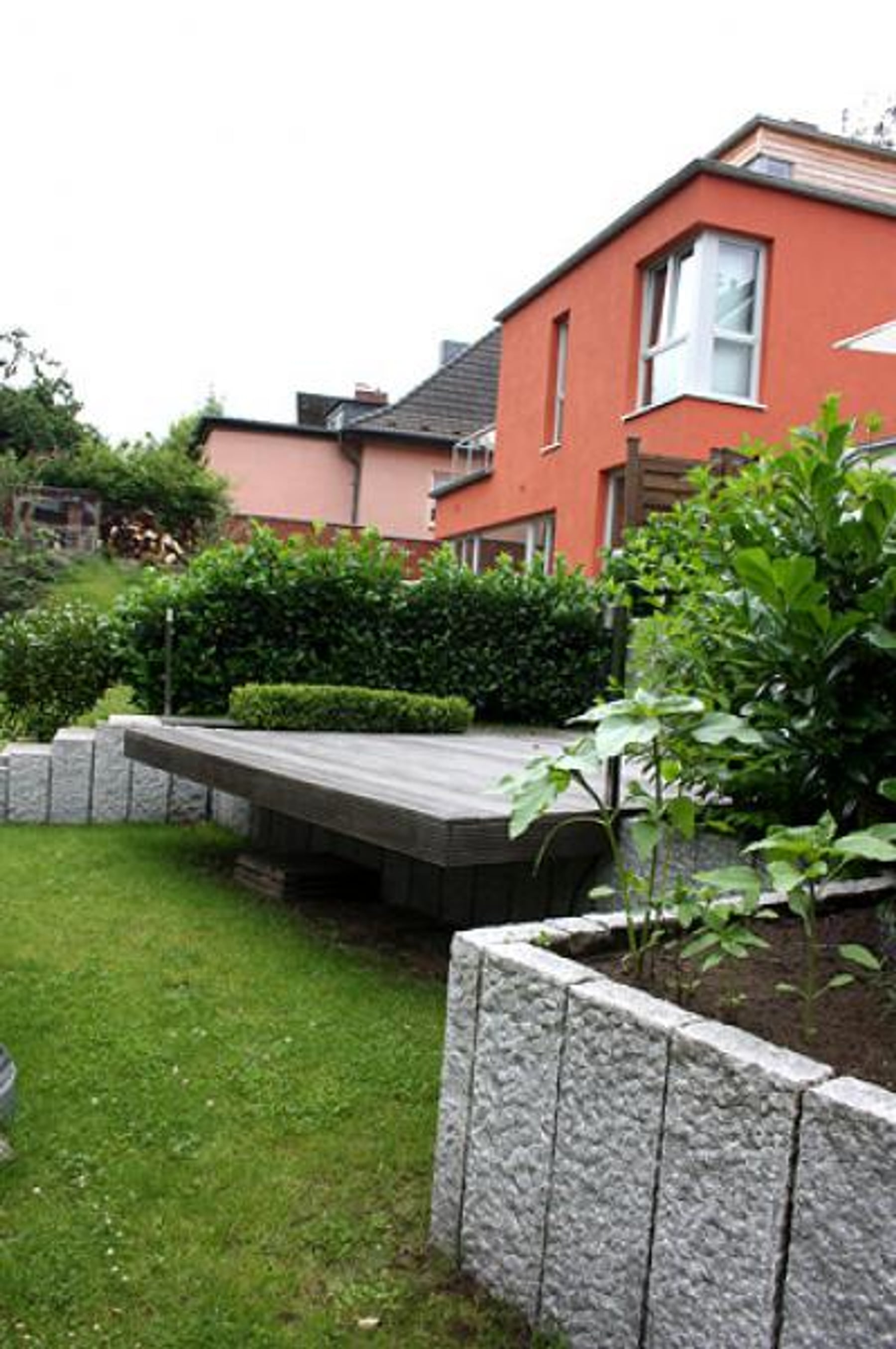 Garten mit Holzdeck, Granitsteinen und Wohnhaus