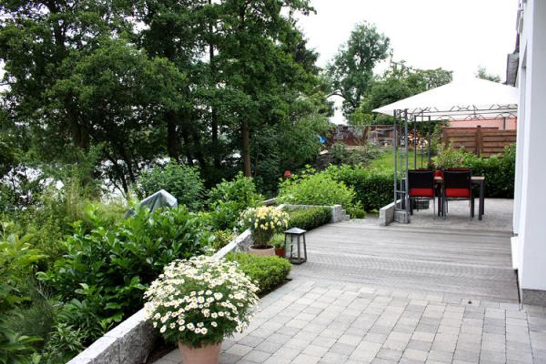 Terrassenanlage mit Pflastersteinen, Bepflanzung und Pavillon